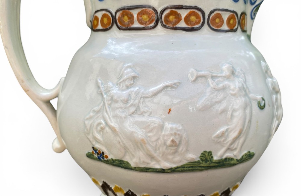 A late 18th-century relief-moulded Prattware ceramic jug featuring polychrome oxide highlights depicting naval battle motifs against an off-white background. View VI