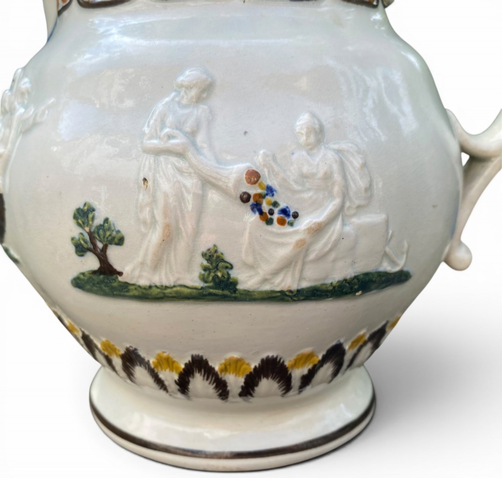 A late 18th-century relief-moulded Prattware ceramic jug featuring polychrome oxide highlights depicting naval battle motifs against an off-white background. View VII