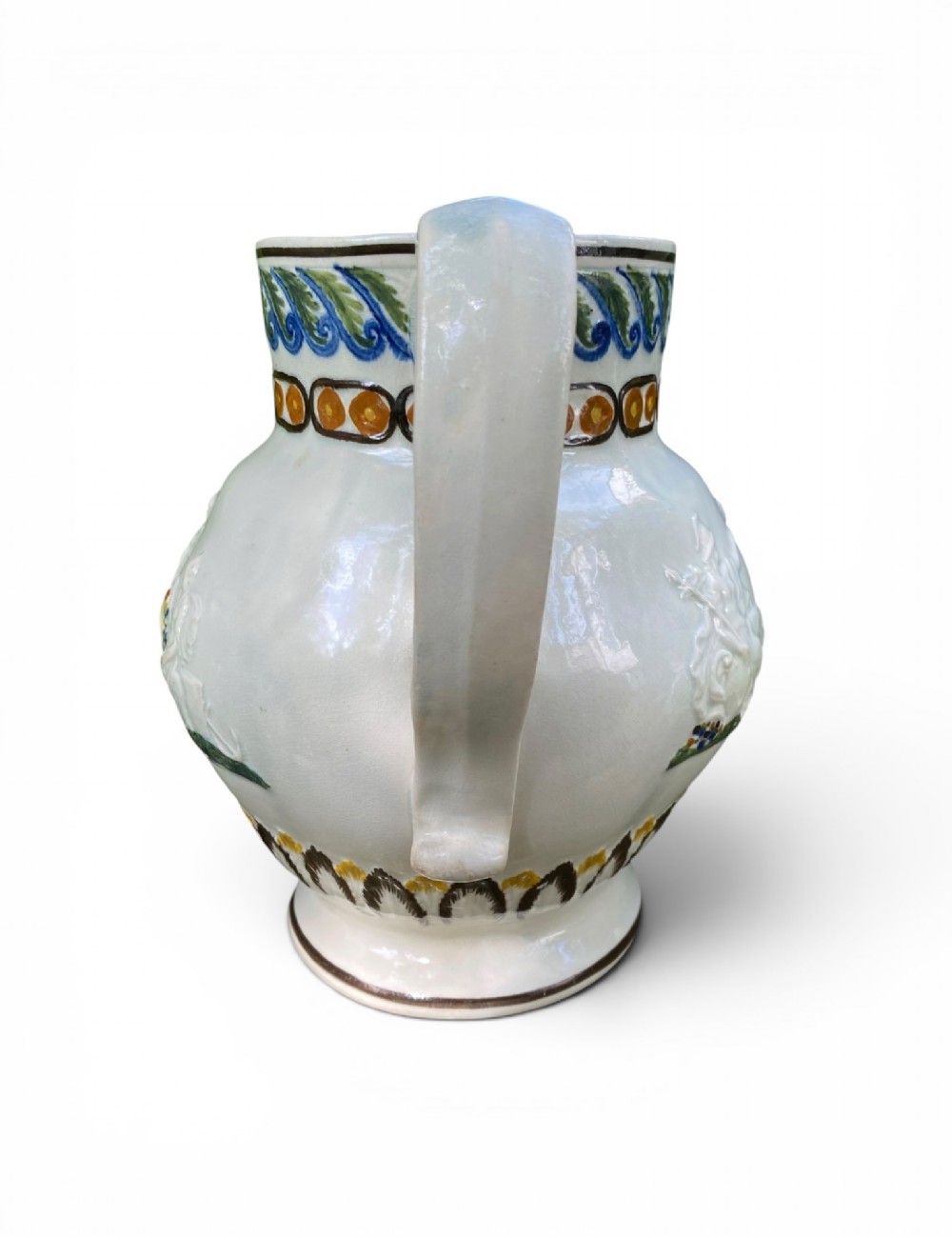 A late 18th-century relief-moulded Prattware ceramic jug featuring polychrome oxide highlights depicting naval battle motifs against an off-white background. View VIII