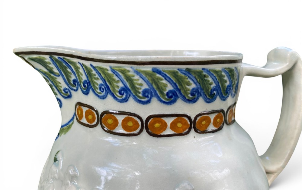 A late 18th-century relief-moulded Prattware ceramic jug featuring polychrome oxide highlights depicting naval battle motifs against an off-white background. View IX