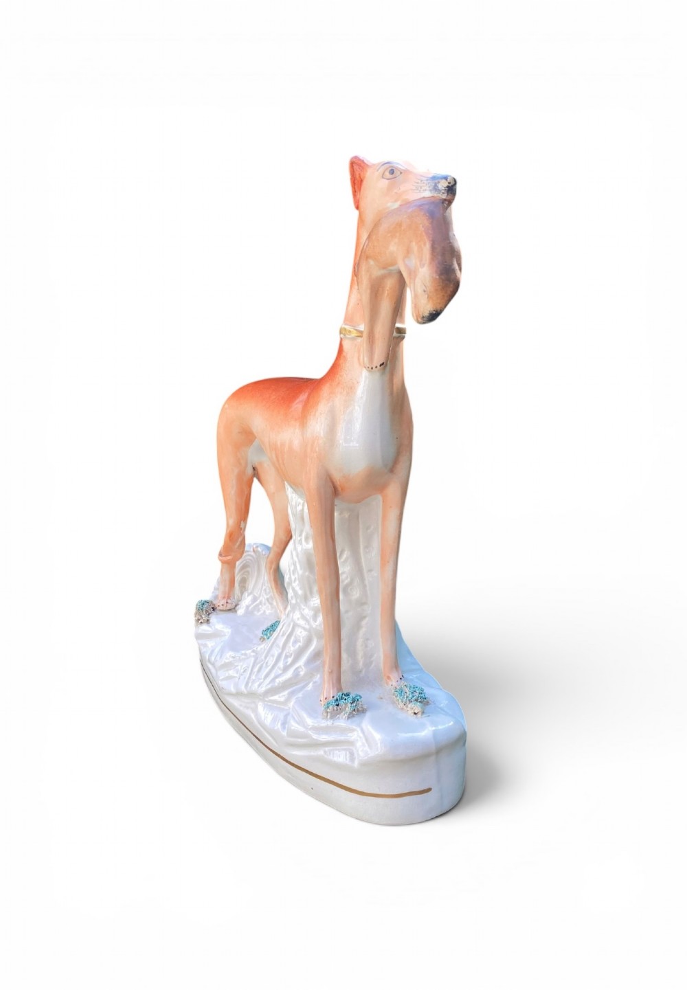 A pair of Victorian Staffordshire earthenware greyhound figurines standing facing each other, each holding a hare in its mouth on a white ceramic base. View III