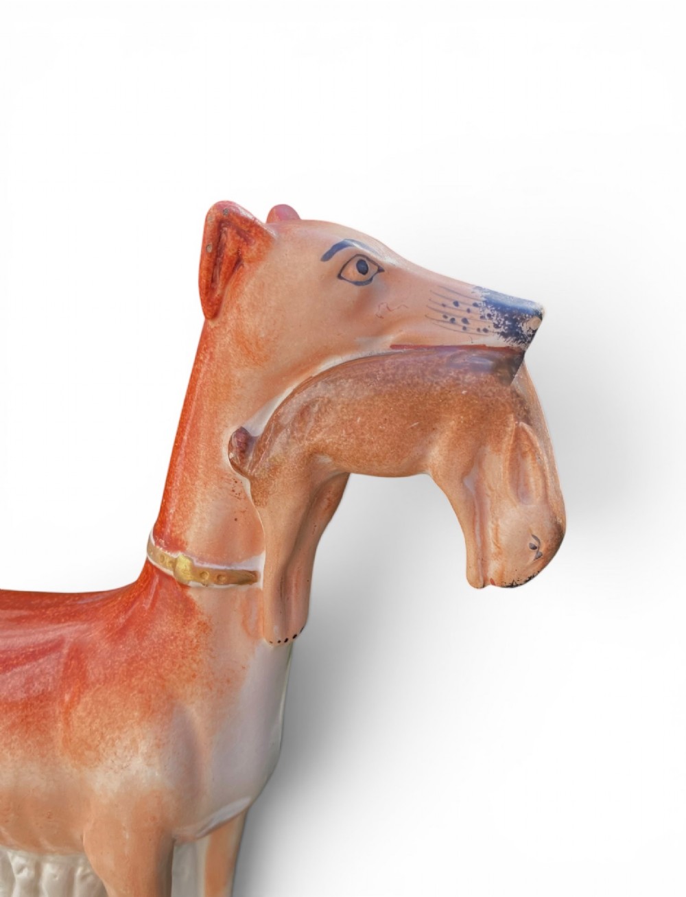 A pair of Victorian Staffordshire earthenware greyhound figurines standing facing each other, each holding a hare in its mouth on a white ceramic base. View V