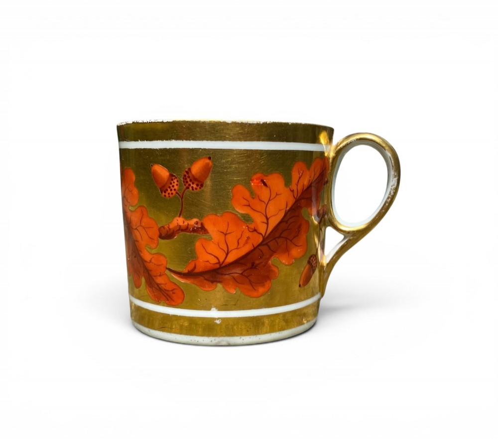 A Regency period Derby porcelain trio featuring two cups and a matching saucer decorated with red oak leaves and heavy gilding. View II