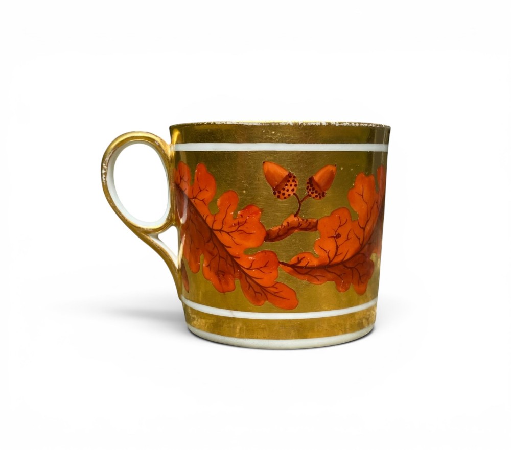 A Regency period Derby porcelain trio featuring two cups and a matching saucer decorated with red oak leaves and heavy gilding. View IV