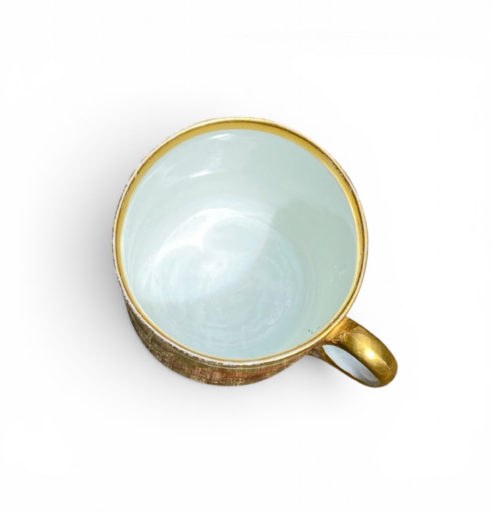 A Regency period Derby porcelain trio featuring two cups and a matching saucer decorated with red oak leaves and heavy gilding. View V