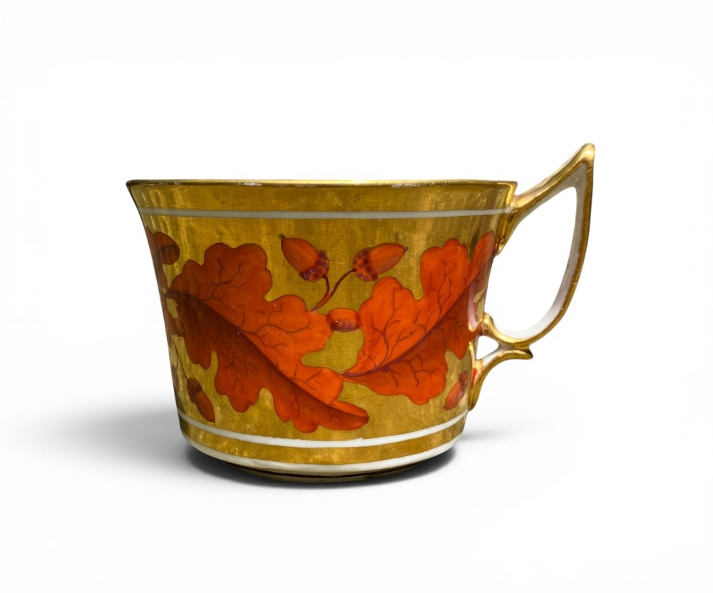 A Regency period Derby porcelain trio featuring two cups and a matching saucer decorated with red oak leaves and heavy gilding. View VII