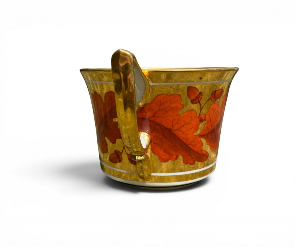 A Regency period Derby porcelain trio featuring two cups and a matching saucer decorated with red oak leaves and heavy gilding. View VIII