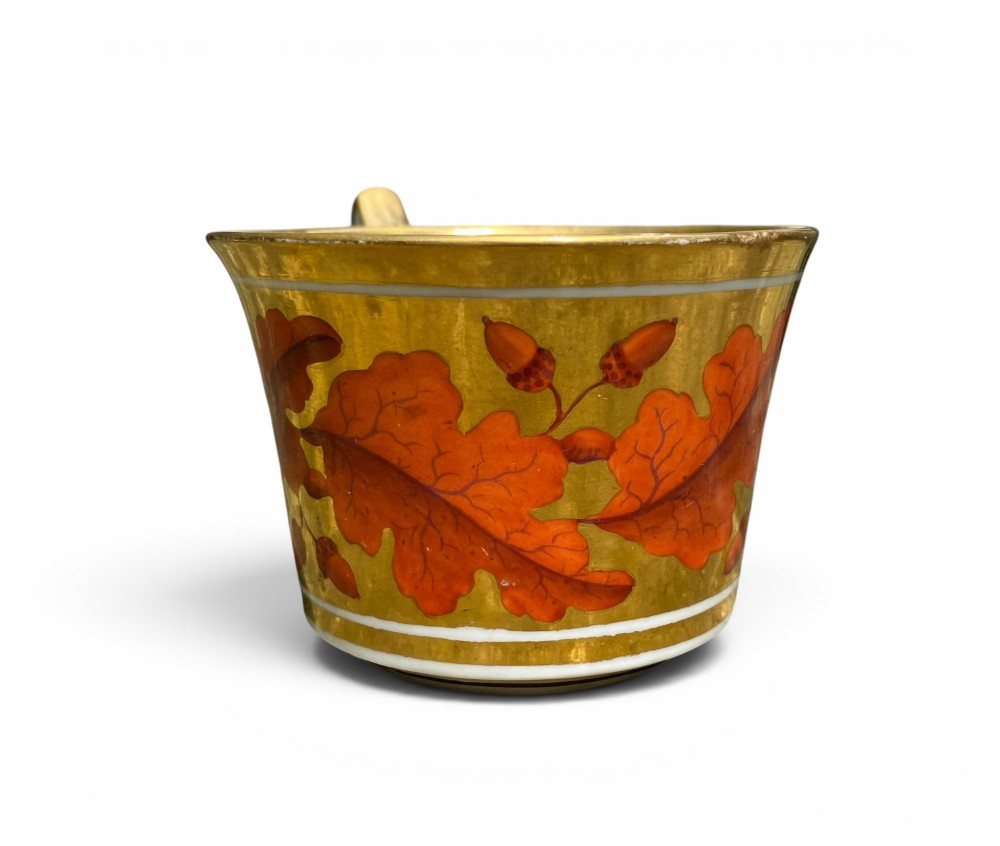 A Regency period Derby porcelain trio featuring two cups and a matching saucer decorated with red oak leaves and heavy gilding. View X