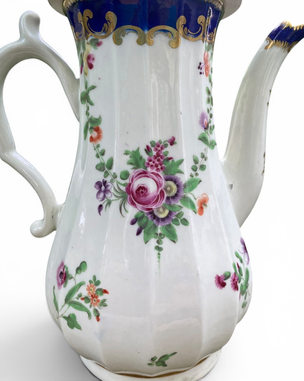 An 18th-century Worcester soft-paste porcelain coffee pot with a cobalt blue rim, hand-painted floral sprays, gilt detailing, and a matching lid with a flower finial. View VI