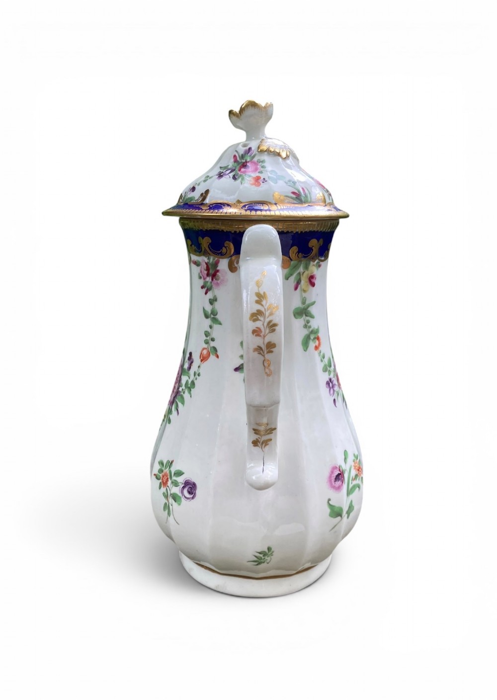 An 18th-century Worcester soft-paste porcelain coffee pot with a cobalt blue rim, hand-painted floral sprays, gilt detailing, and a matching lid with a flower finial. View VIII