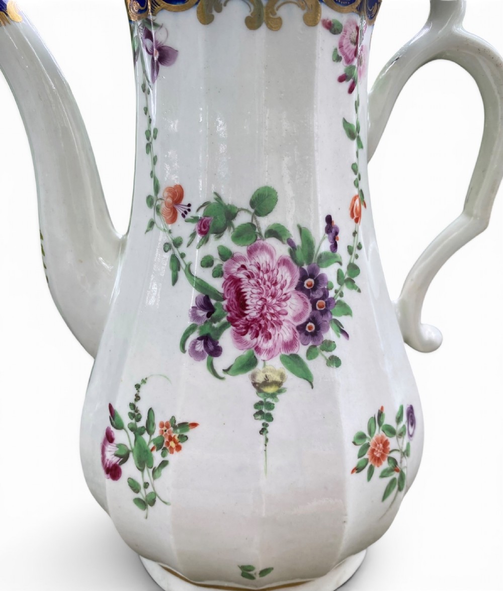 An 18th-century Worcester soft-paste porcelain coffee pot with a cobalt blue rim, hand-painted floral sprays, gilt detailing, and a matching lid with a flower finial. View IX