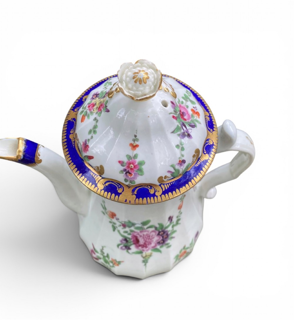 An 18th-century Worcester soft-paste porcelain coffee pot with a cobalt blue rim, hand-painted floral sprays, gilt detailing, and a matching lid with a flower finial. View XI