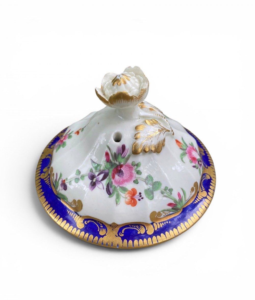 An 18th-century Worcester soft-paste porcelain coffee pot with a cobalt blue rim, hand-painted floral sprays, gilt detailing, and a matching lid with a flower finial. View XIV