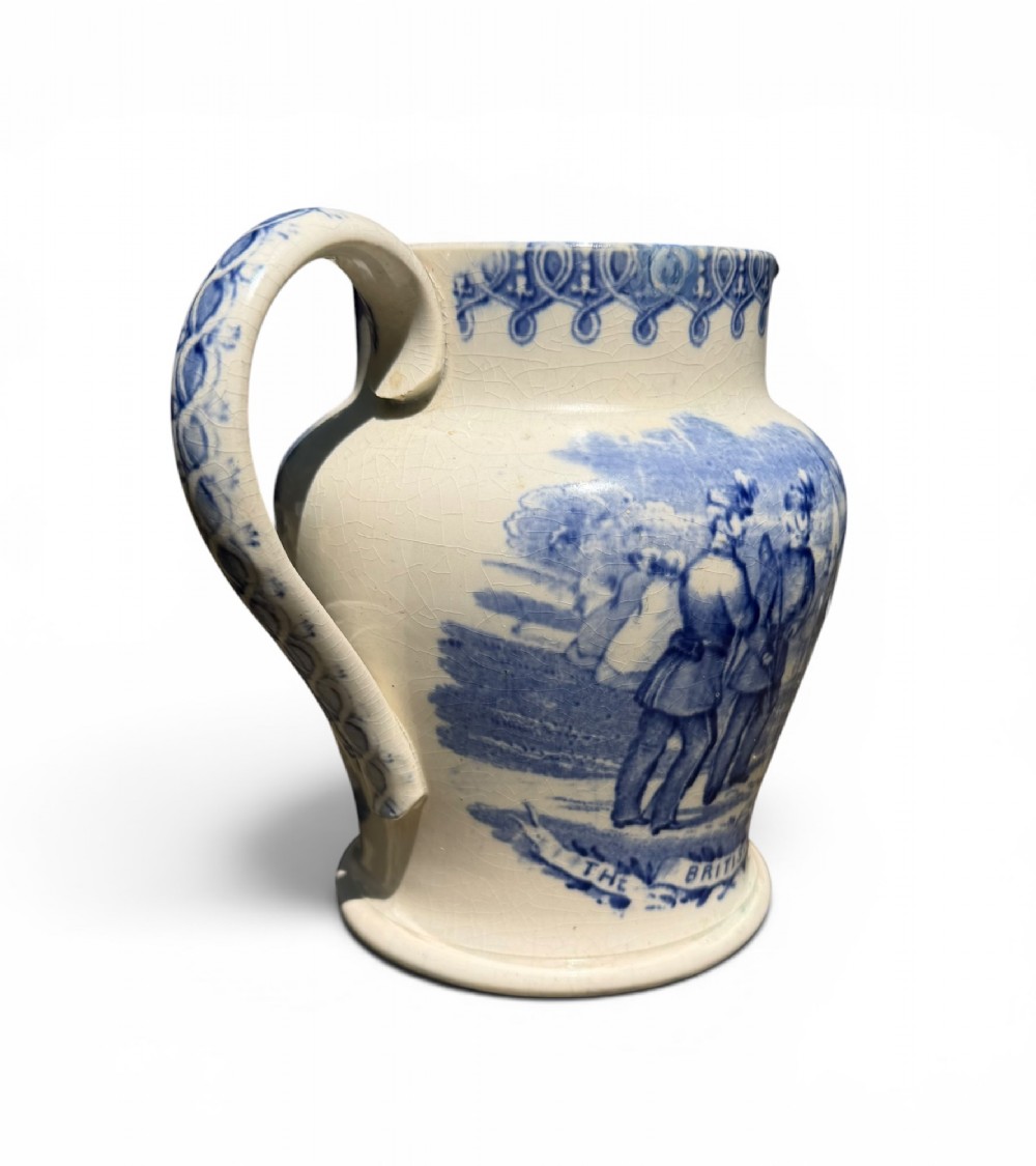 A cream earthenware jug featuring cobalt blue transferware depicting military figures labeled The British Volunteers. View IV