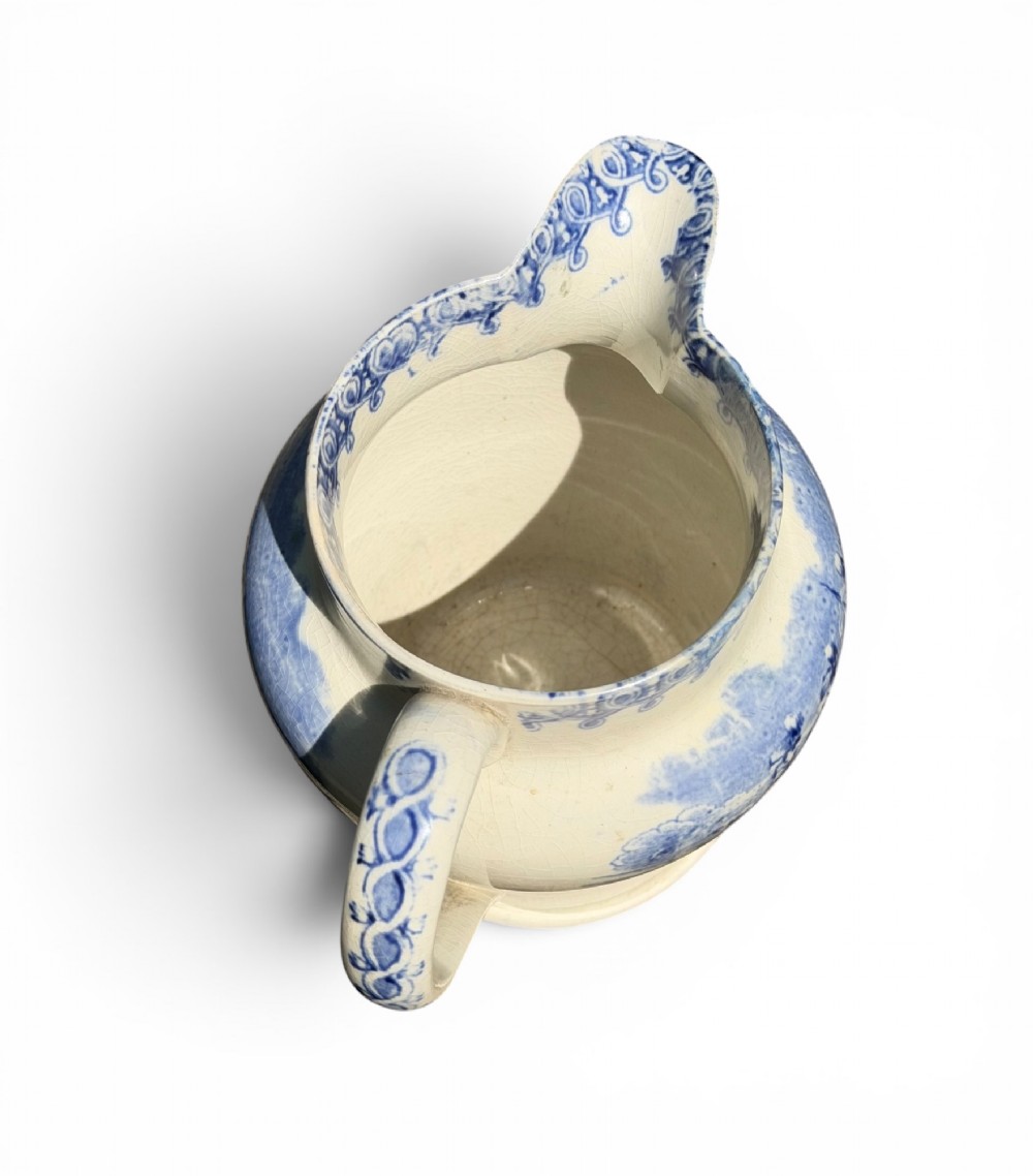 A cream earthenware jug featuring cobalt blue transferware depicting military figures labeled The British Volunteers. View V