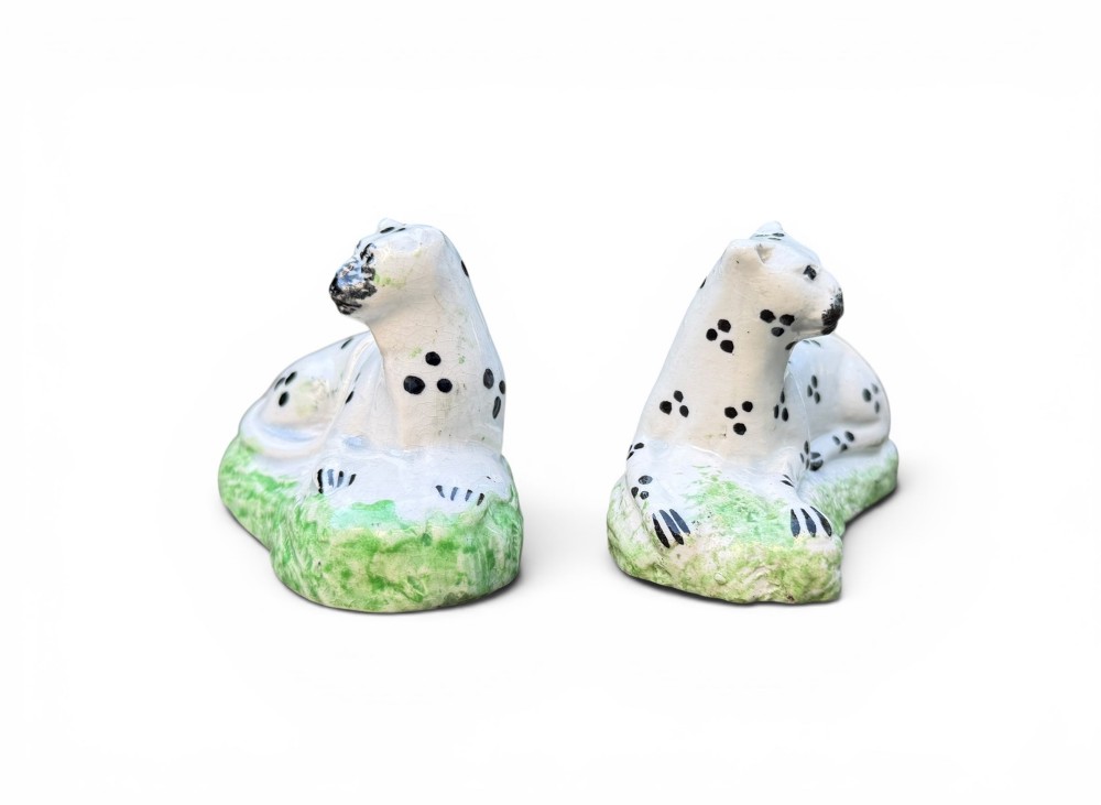 A pair of small antique white pearlware figures of recumbent spotted leopards resting on moulded green bases. View II