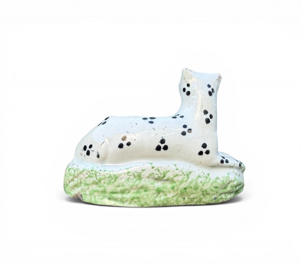 A pair of small antique white pearlware figures of recumbent spotted leopards resting on moulded green bases. View IV