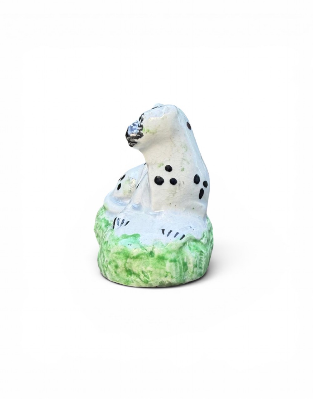 A pair of small antique white pearlware figures of recumbent spotted leopards resting on moulded green bases. View IX
