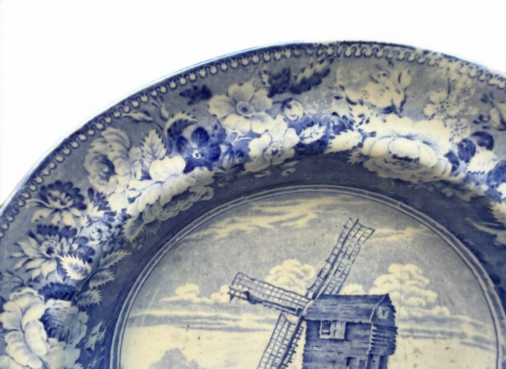 A circular blue and white transferware pottery dish decorated with a central windmill scene and a wide floral border. View III