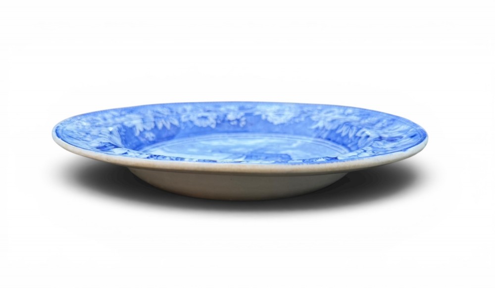 A circular blue and white transferware pottery dish decorated with a central windmill scene and a wide floral border. View IV
