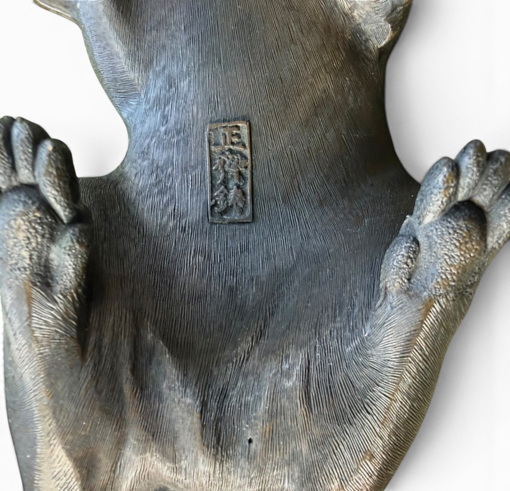 A Japanese bronze sculpture depicting a seated tanuki resting its paw on corn husks, featuring textured fur engraving and a dark patinated finish. View VIII