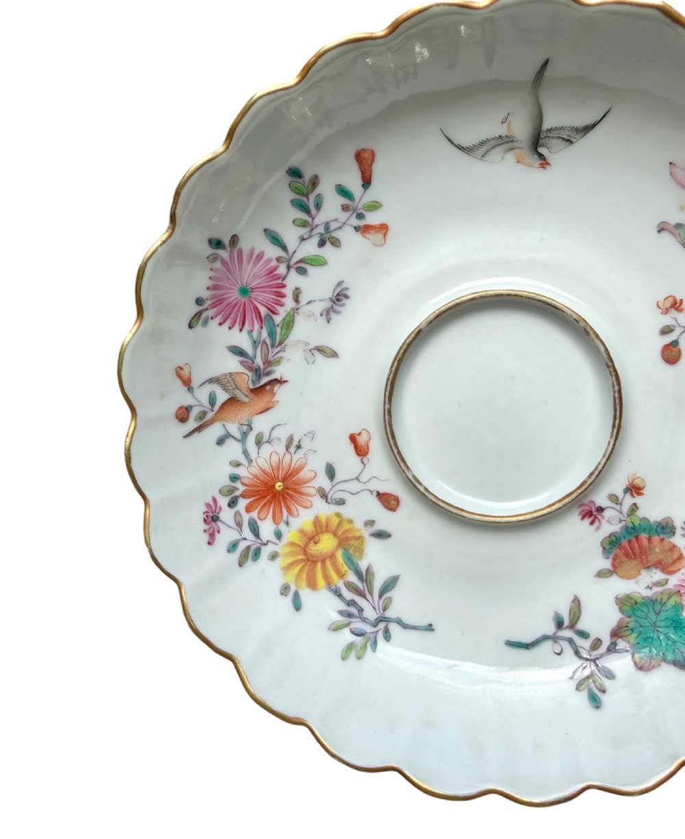 A Chinese export famille rose porcelain twin-handled cup and scalloped stand decorated with hand-painted floral motifs, birds, and gilt edges. View IV