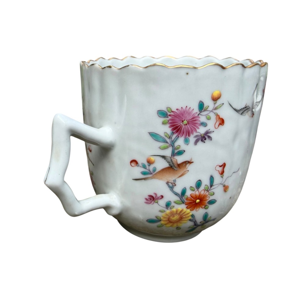 A Chinese export famille rose porcelain twin-handled cup and scalloped stand decorated with hand-painted floral motifs, birds, and gilt edges. View IX