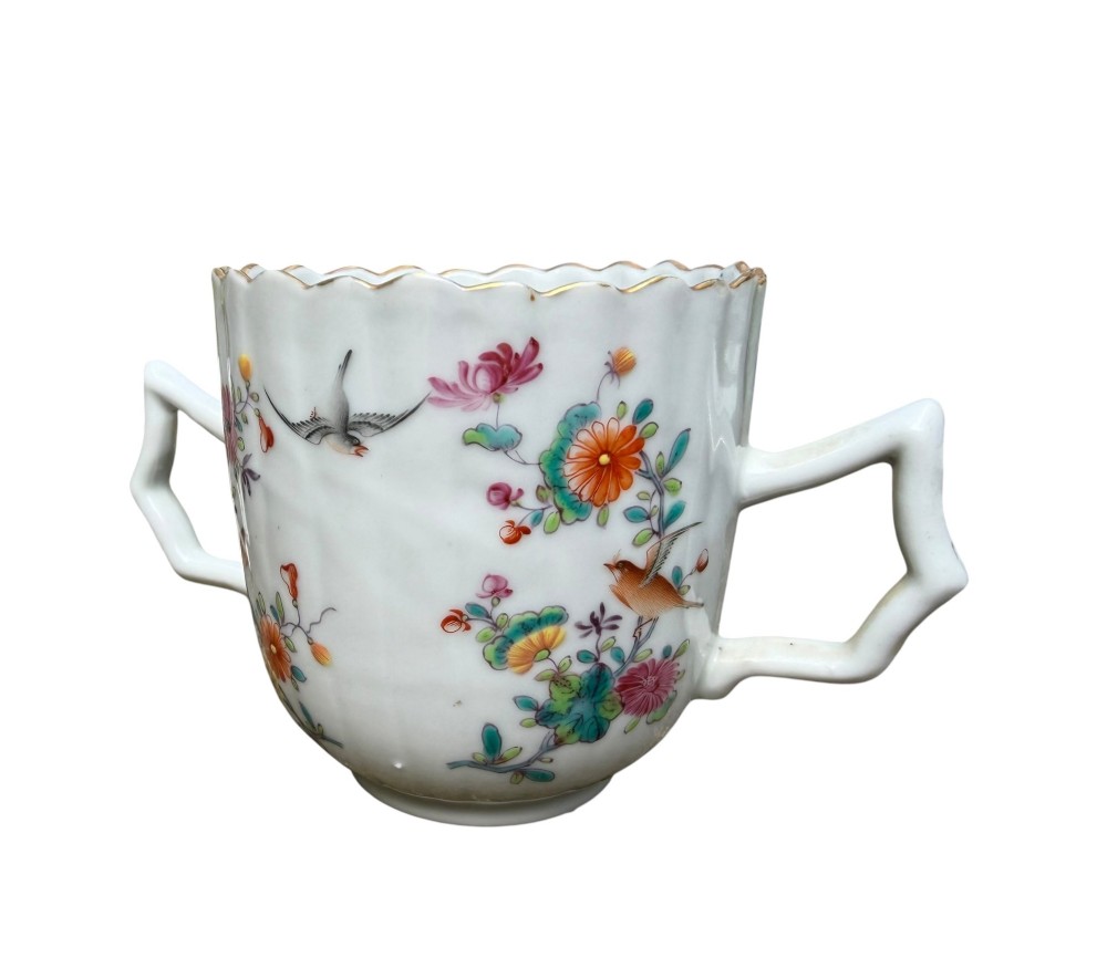 A Chinese export famille rose porcelain twin-handled cup and scalloped stand decorated with hand-painted floral motifs, birds, and gilt edges. View XII