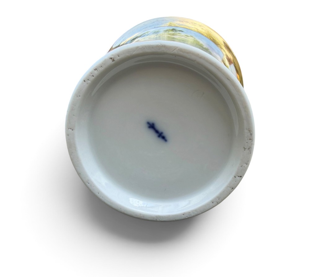 An early nineteenth-century flared porcelain cabinet cup featuring a hand-painted landscape scene with a river, bridge, and hilltop ruins above inscribed German text, finished with a gilded rim and elevated handle. View XI