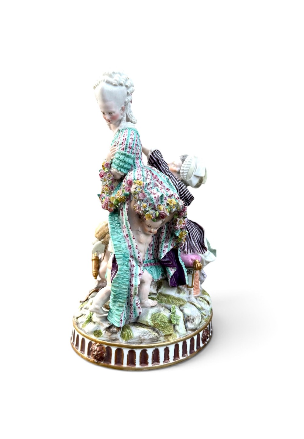An eighteenth-century polychrome hard-paste porcelain figurine group depicting two classical figures and a cherub beside an overturned basket of eggs on a moulded fluted base. View III