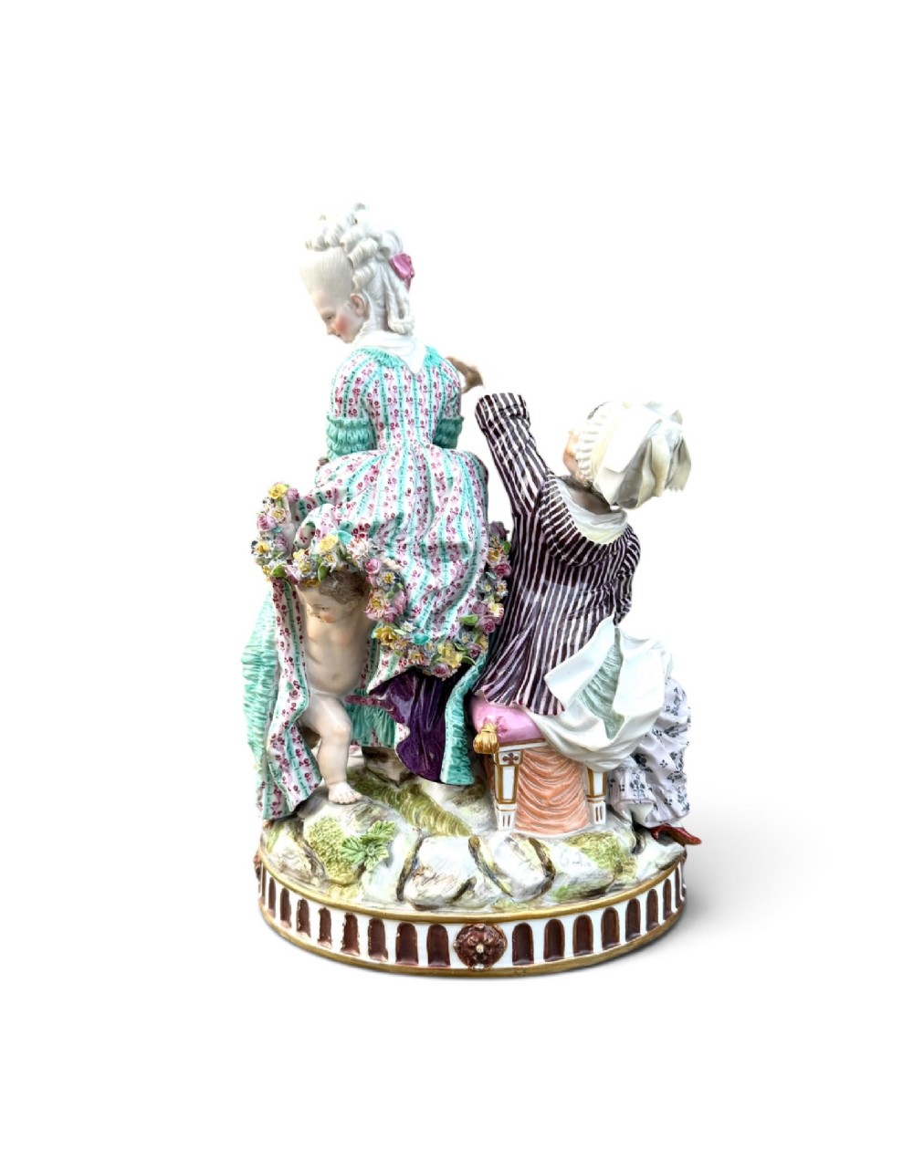 An eighteenth-century polychrome hard-paste porcelain figurine group depicting two classical figures and a cherub beside an overturned basket of eggs on a moulded fluted base. View IV