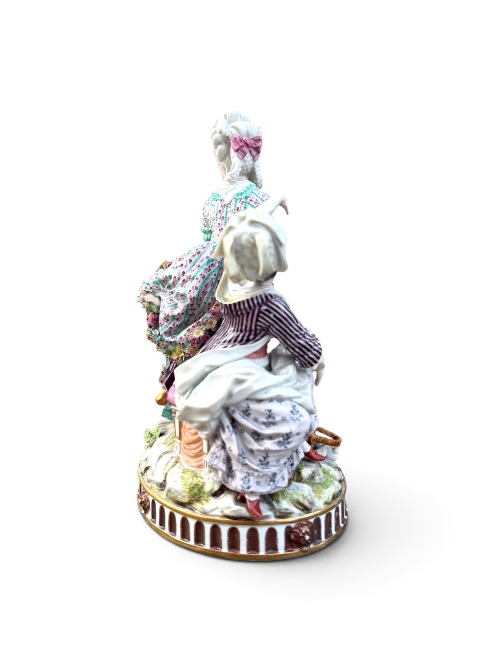 An eighteenth-century polychrome hard-paste porcelain figurine group depicting two classical figures and a cherub beside an overturned basket of eggs on a moulded fluted base. View V