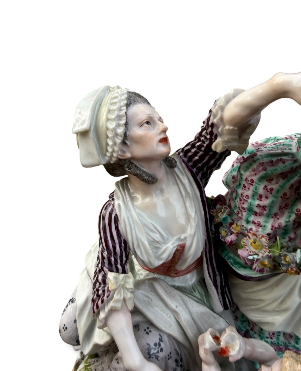An eighteenth-century polychrome hard-paste porcelain figurine group depicting two classical figures and a cherub beside an overturned basket of eggs on a moulded fluted base. View VII