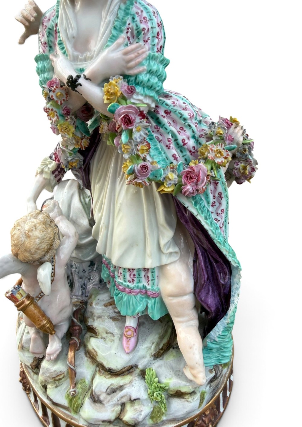 An eighteenth-century polychrome hard-paste porcelain figurine group depicting two classical figures and a cherub beside an overturned basket of eggs on a moulded fluted base. View X