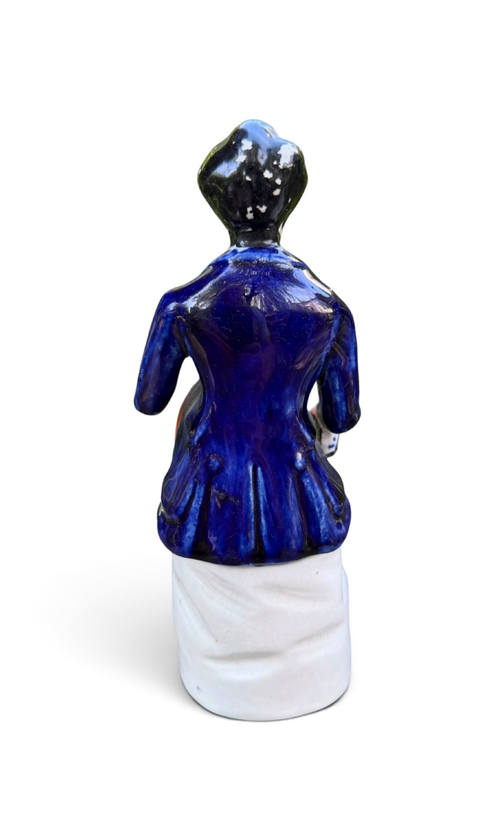 An antique Victorian Staffordshire earthenware figure depicting Lord Shaftesbury in a cobalt blue coat seated with a young child in an orange jacket on a white base. View III