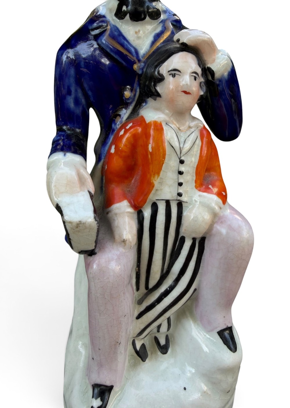 An antique Victorian Staffordshire earthenware figure depicting Lord Shaftesbury in a cobalt blue coat seated with a young child in an orange jacket on a white base. View VI