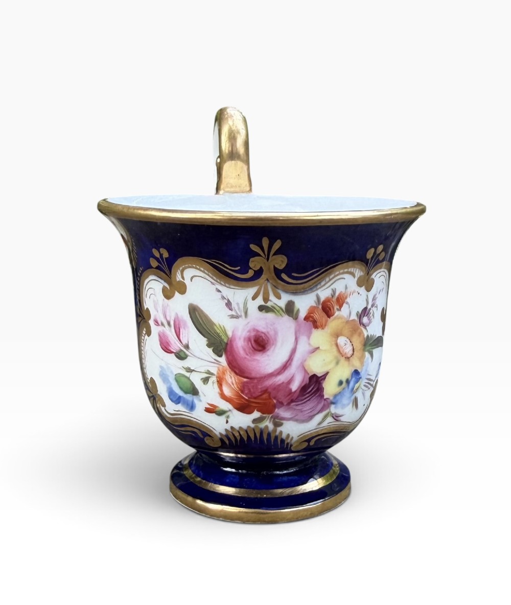 An antique Regency period Coalport porcelain cabinet cup and saucer featuring cobalt blue ground with gilt cartouches and hand-painted floral reserves. View VI
