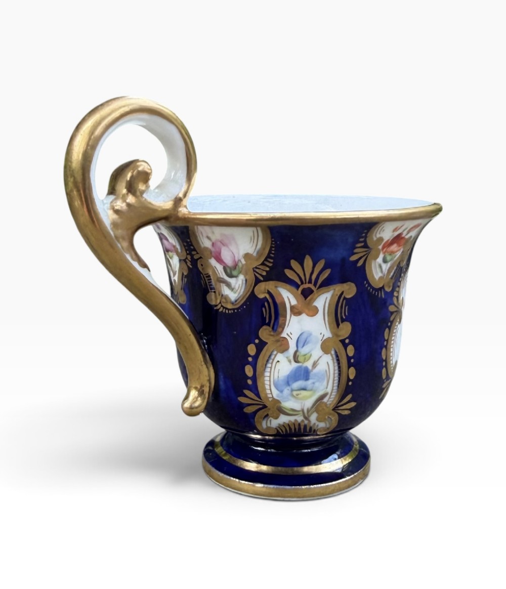 An antique Regency period Coalport porcelain cabinet cup and saucer featuring cobalt blue ground with gilt cartouches and hand-painted floral reserves. View VIII