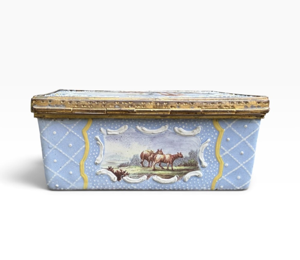 A rectangular Georgian enamel snuff box featuring a light blue trellis background, gilt metal mounts, and hand-painted pastoral scenes in central cartouches. View V