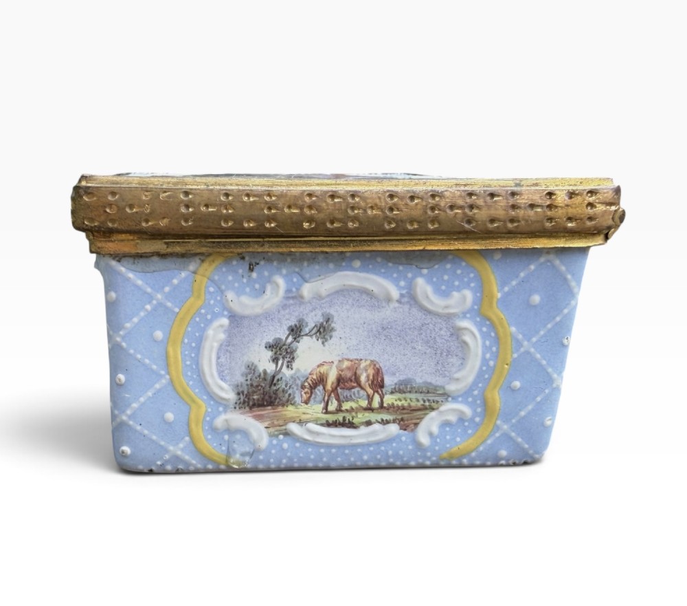 A rectangular Georgian enamel snuff box featuring a light blue trellis background, gilt metal mounts, and hand-painted pastoral scenes in central cartouches. View VI