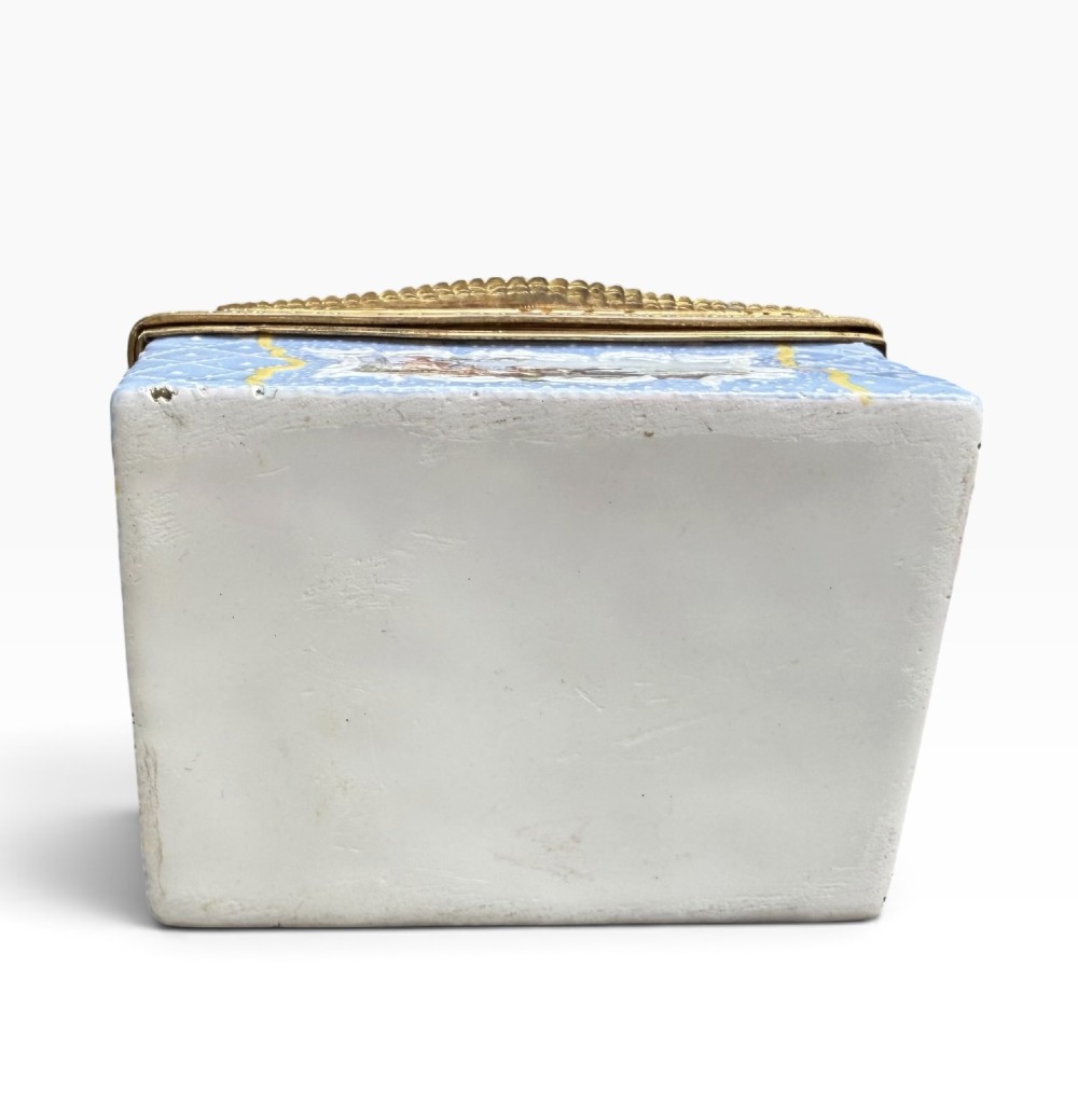 A rectangular Georgian enamel snuff box featuring a light blue trellis background, gilt metal mounts, and hand-painted pastoral scenes in central cartouches. View IX