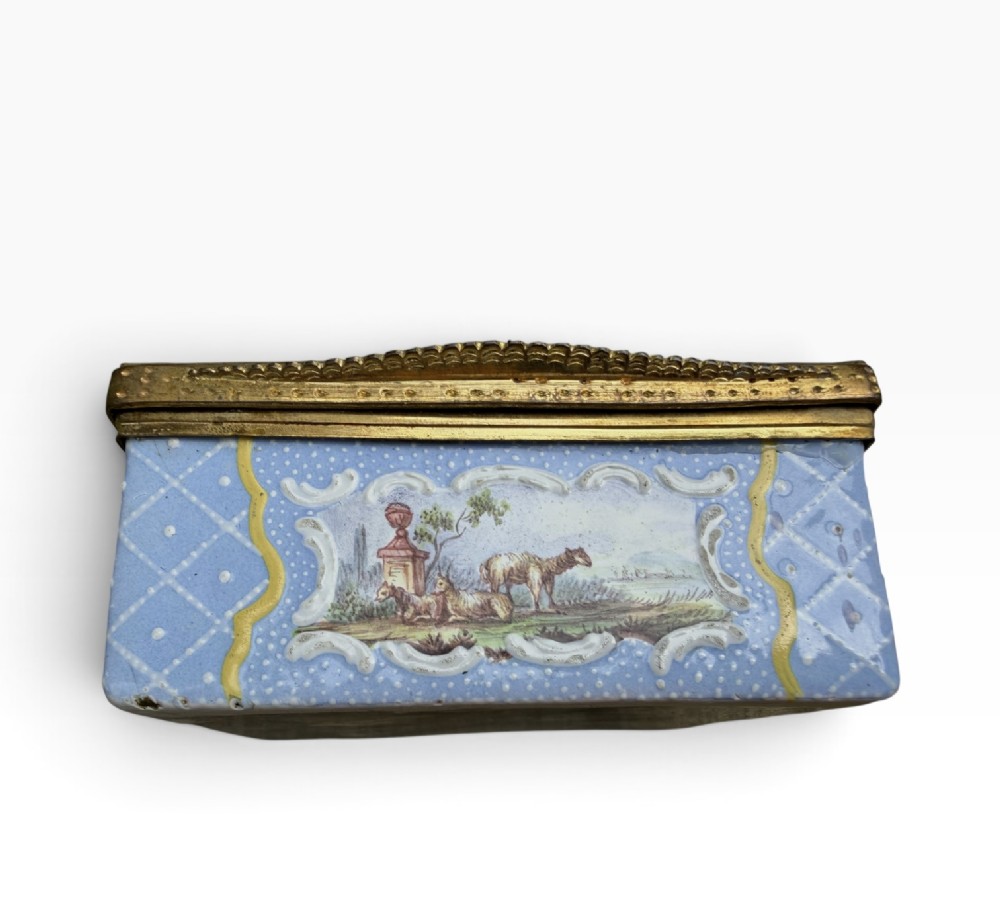 A rectangular Georgian enamel snuff box featuring a light blue trellis background, gilt metal mounts, and hand-painted pastoral scenes in central cartouches. View X