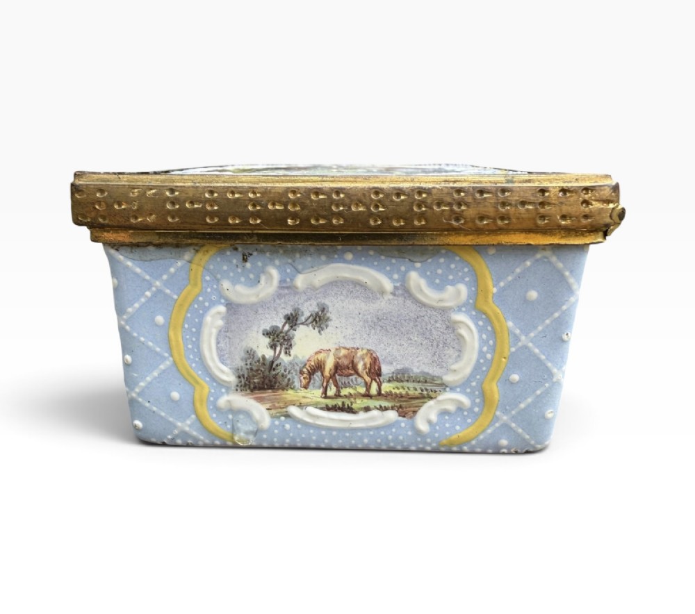 A rectangular Georgian enamel snuff box featuring a light blue trellis background, gilt metal mounts, and hand-painted pastoral scenes in central cartouches. View XII