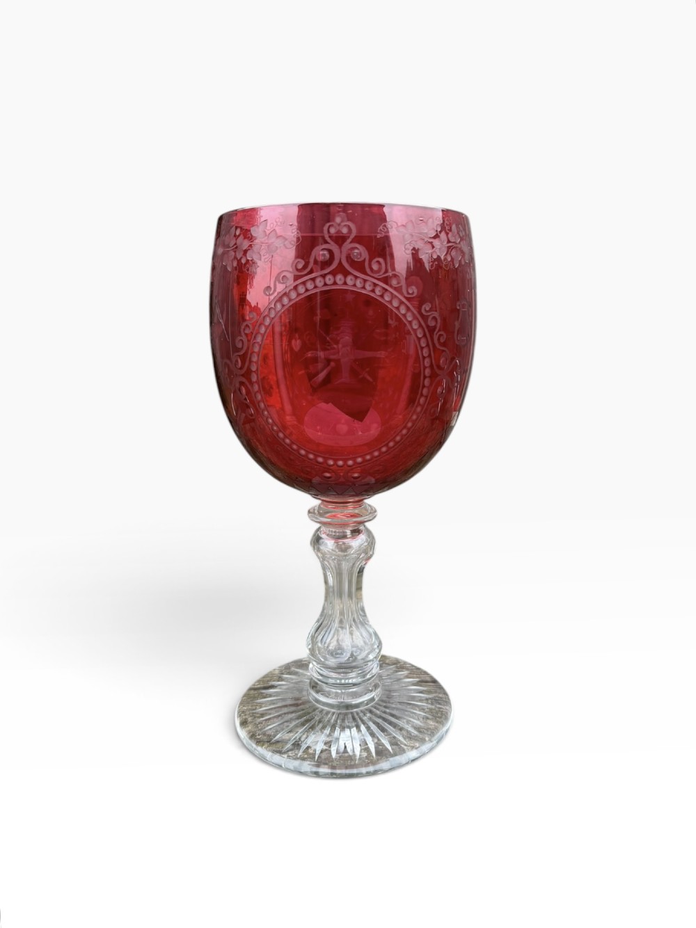 A Victorian cranberry glass goblet with intricately wheel-engraved Masonic symbols on a red bowl, supported by a clear knopped glass stem and a star-cut circular base. View II