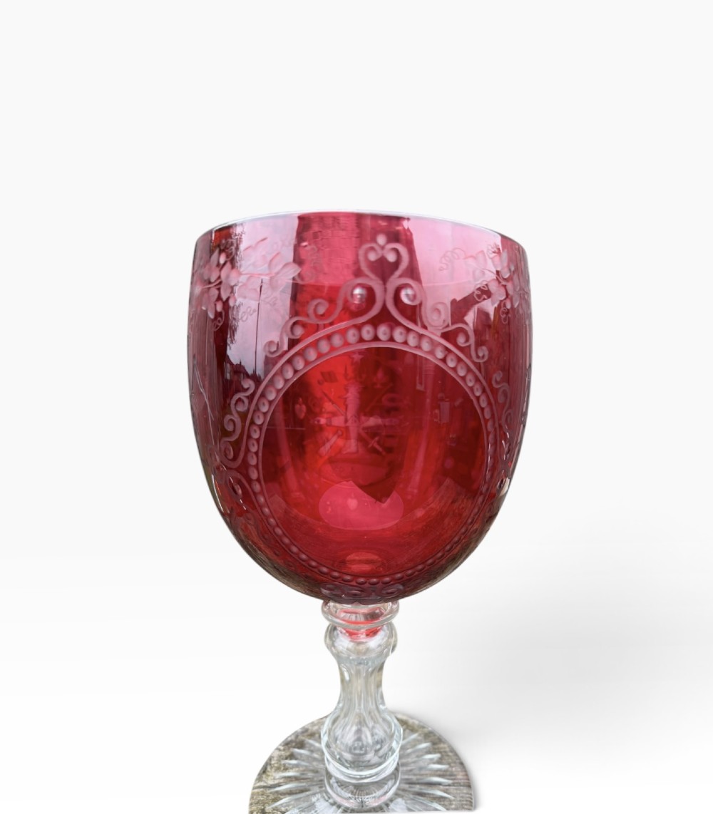 A Victorian cranberry glass goblet with intricately wheel-engraved Masonic symbols on a red bowl, supported by a clear knopped glass stem and a star-cut circular base. View XI
