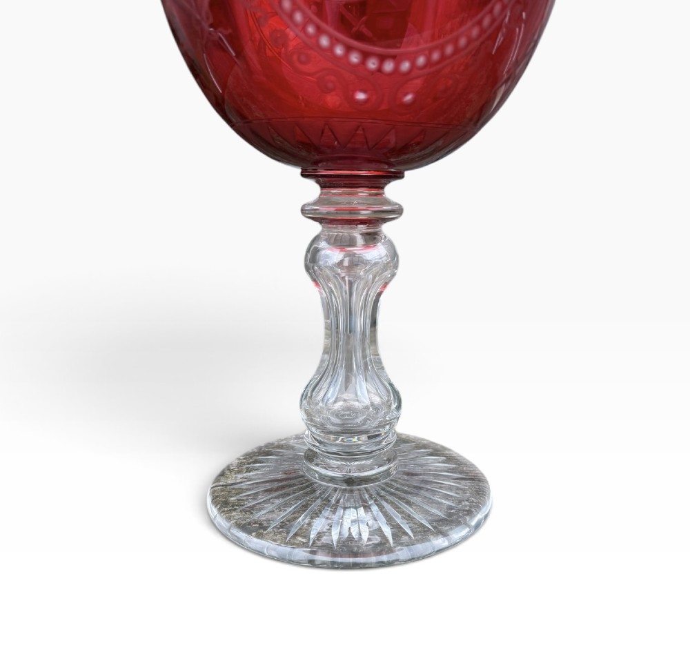 A Victorian cranberry glass goblet with intricately wheel-engraved Masonic symbols on a red bowl, supported by a clear knopped glass stem and a star-cut circular base. View XII