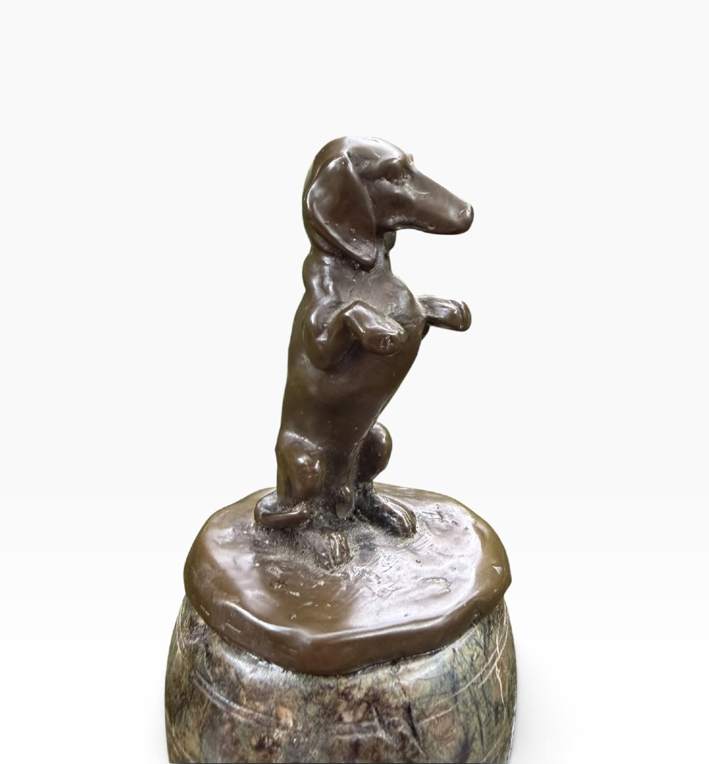 A small dark bronze sculpture of a dachshund standing on its hind legs in a begging position, mounted atop a carved marble barrel base. View VI