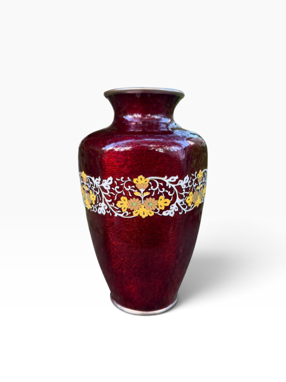A baluster-shaped Japanese ginbari cloisonne vase featuring deep crimson enamel over foil, decorated with a band of yellow blossoms and white scrolling foliage around the center. View II