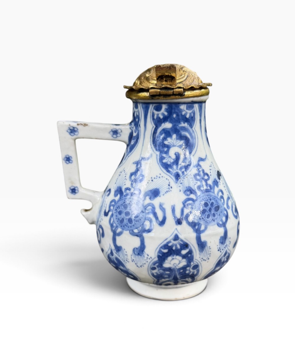 A blue and white Kangxi period Chinese porcelain jug with hand-painted floral decoration, an angular ceramic handle, and a chased gilt-metal lid. View IV