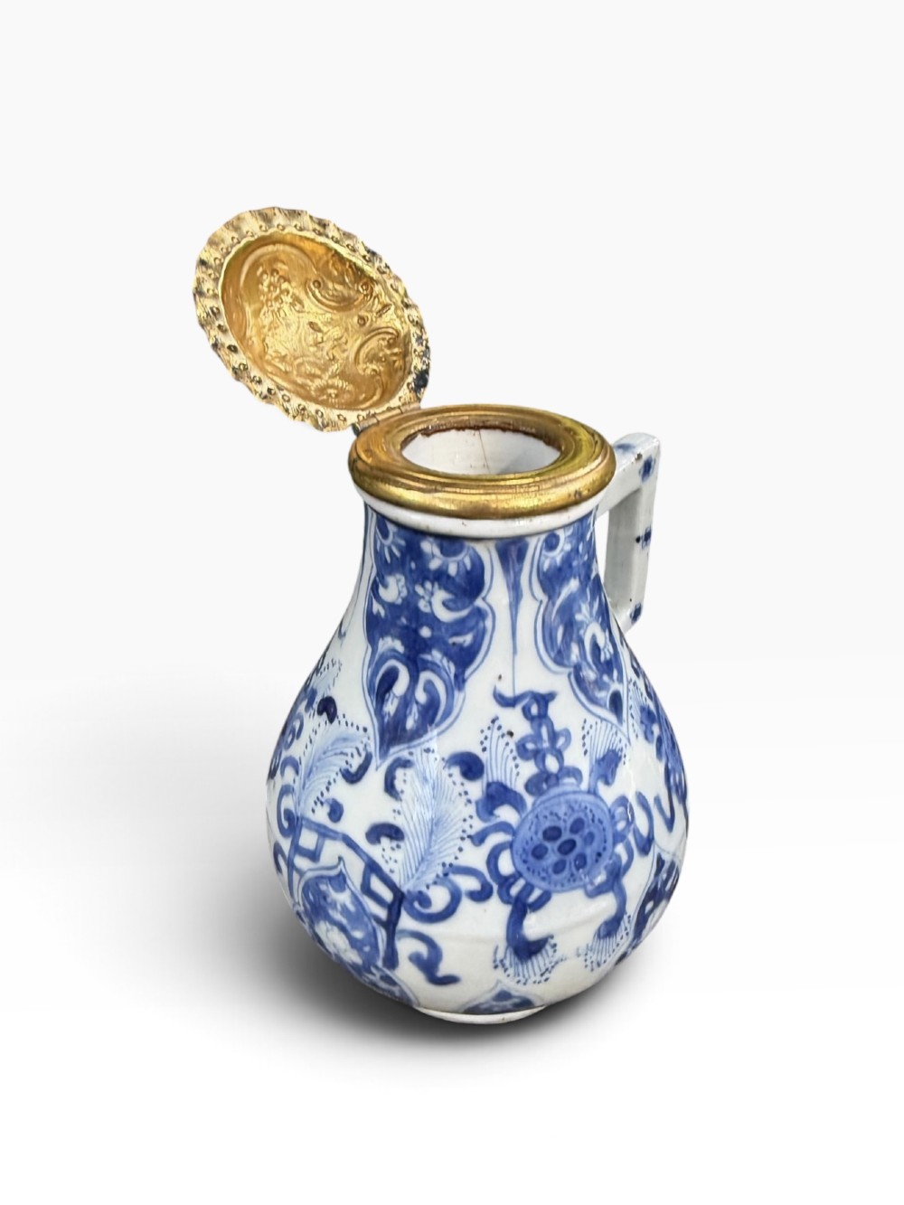 A blue and white Kangxi period Chinese porcelain jug with hand-painted floral decoration, an angular ceramic handle, and a chased gilt-metal lid. View VI